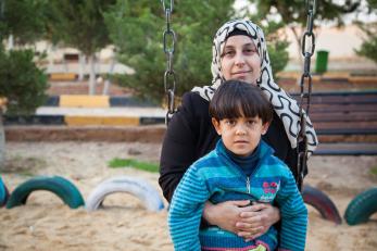 A woman holds her young son on her lap on a swing in jordan