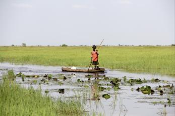 Person navigating a small wooden canoe in shallow water