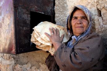 A woman holds a stack of bread
