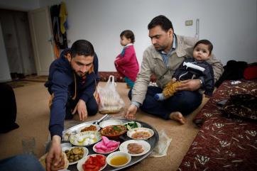 Bashar with family members seated on floor eating a meal