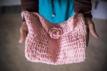 Hands holding a pink crocheted purse