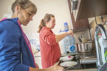 September 2023, mykolaiv, ukraine. olena (33, blue shirt) and oleksandra (28, red shirt) cook in the kitchen at a shelter run by mercy corps partner organization perspectyva. 