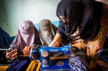 Three women in afghanistan learning to use a sewing machine