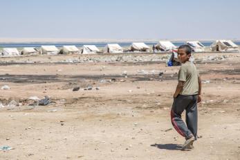 Boy walking toward a row of white tents in syria