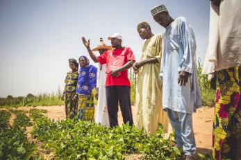 Men and women with a mercy corps employee standing in a field in niger