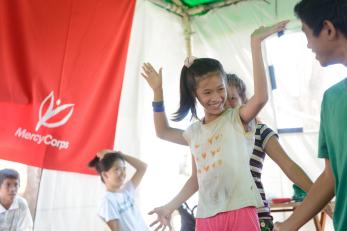 Children dancing and smiling in a child-centered space in the the philippines.