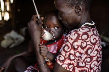 Man feeding young child in south sudan