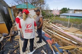 Mercy corps employees speaking with a man impacted by hurricane maria