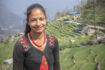 Nepalese woman in front of terraced fields of crops