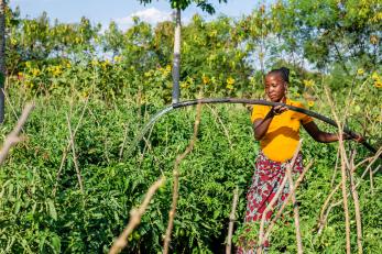 Tanzanian woman working with irrigation equipment in agricultural setting.