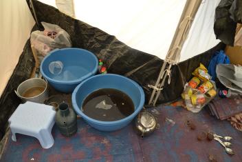 A makeshift kitchen in the back of one family’s tent. A dishwashing area, a place to make tea, a trash bag.