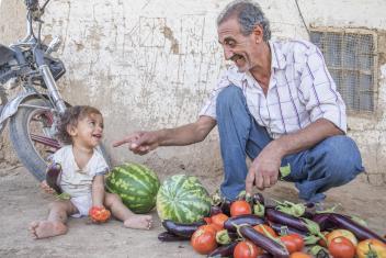Abu Goubran with his granddaughter Wia, 1, and a pile of freshly harvested eggplant, tomatoes and watermelon. Farming expertise like his will be critical to Syria's communities as they look to the future. Local farmers come here for training sessions on innovative farming techniques. “I’m so happy to share what I know,” he says.