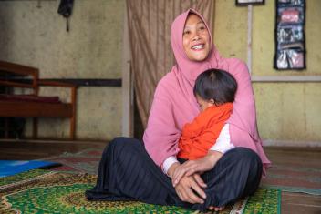 Aryanti cradles her 2-year-old daughter. She received entrepreneurship and business training to help her start her own business, making and selling snack chips made from local Indonesian spices, herbs, and root vegetables.